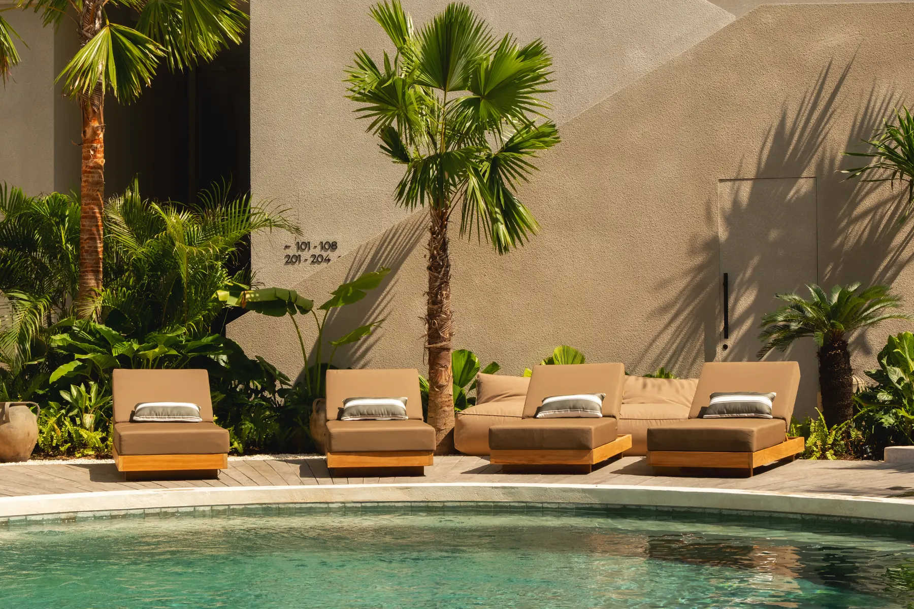 The pool terrace at the hotel — loungers and palms along the water in the morning sun